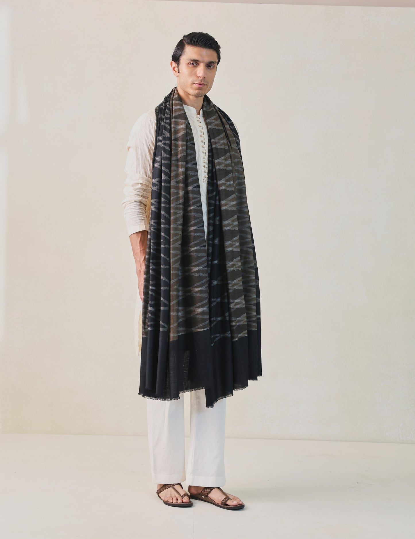 A man wearing a black, brown, and gray pashmina shawl with a geometric pattern.