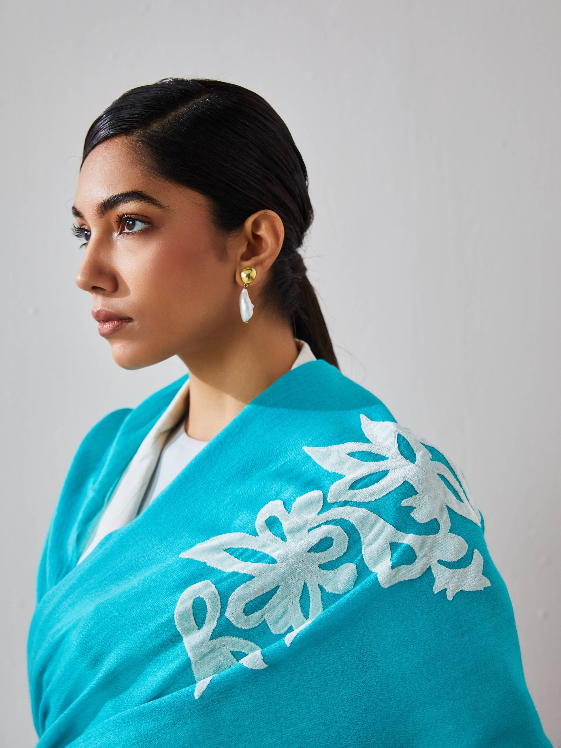 Model is wearing a firozi blue Velvet affair cashmere stole with white applique from Shaza.