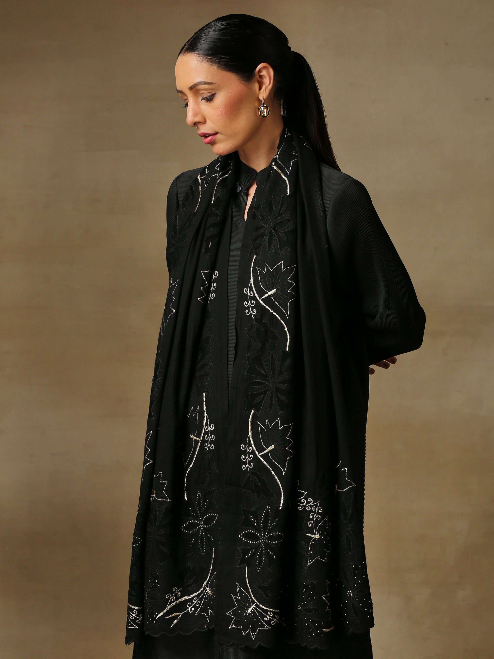Model is wearing a Vineyard Zaywar stole featuring cutwork vine pattern bordered with zari details and hand embellished with fine swarovski, in a black colour. 