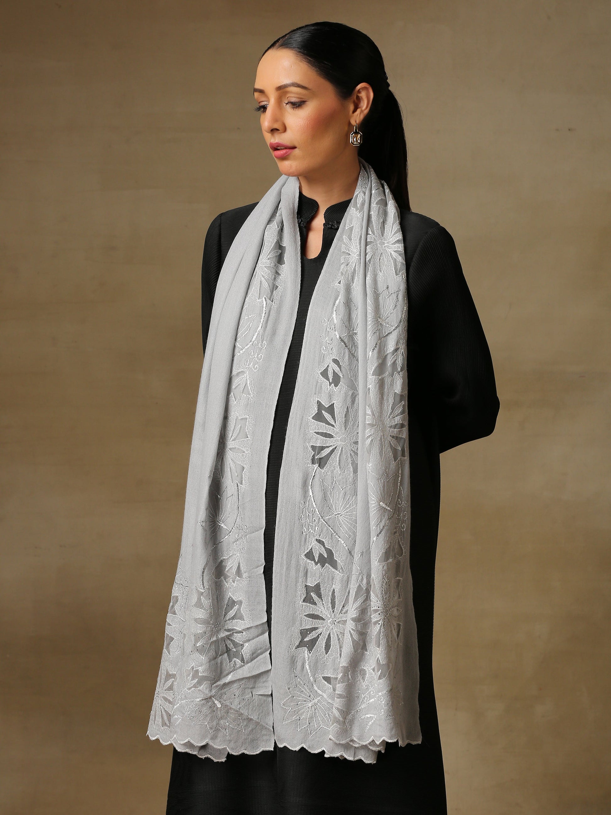Model is wearing a Vineyard Zaywar stole featuring cutwork vine pattern bordered with zari details and hand embellished with fine swarovski, in a ice blue colour.