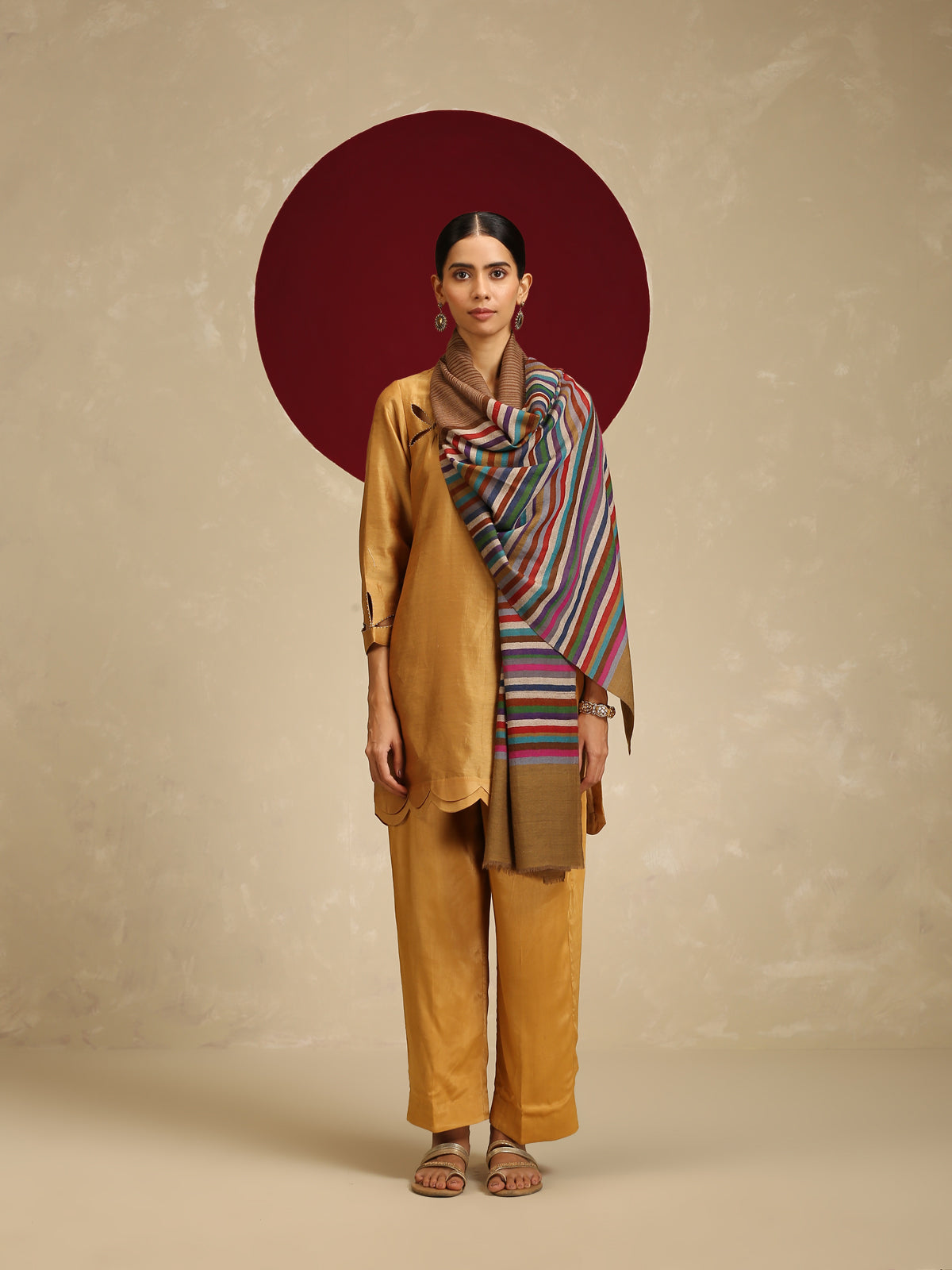 Model is wearing a Qazah stole featuring multicoloured stripes on a gold base.