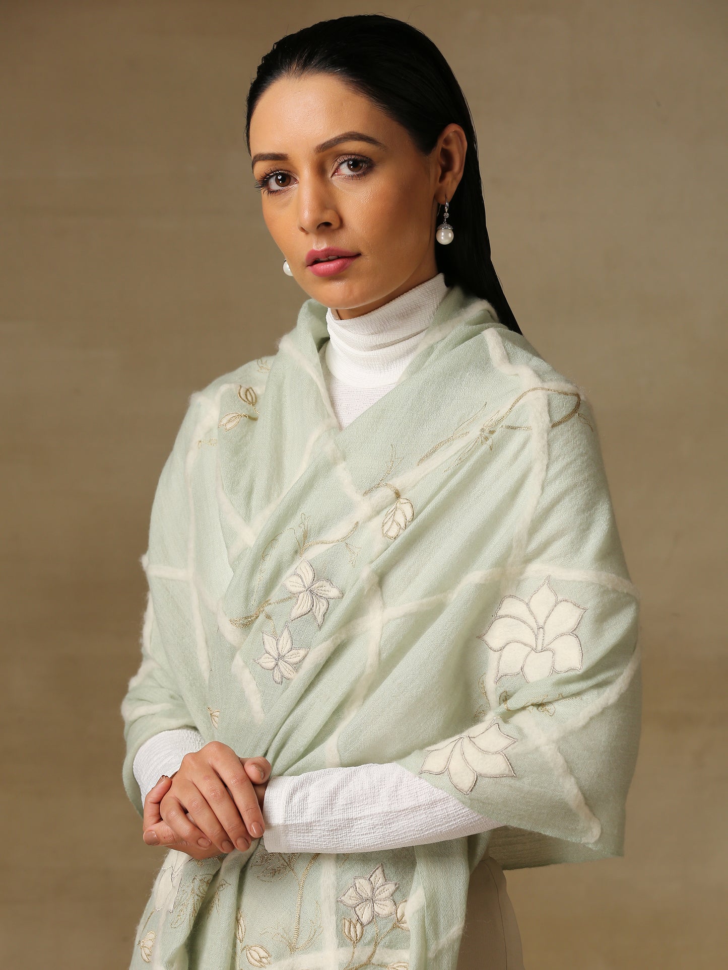 Model is wearing the Daisy pashmina stole in mint green from Shaza, featuring threadwork of interwoven lines, applique of daisy figures and zari work on handloomed pashmina.
