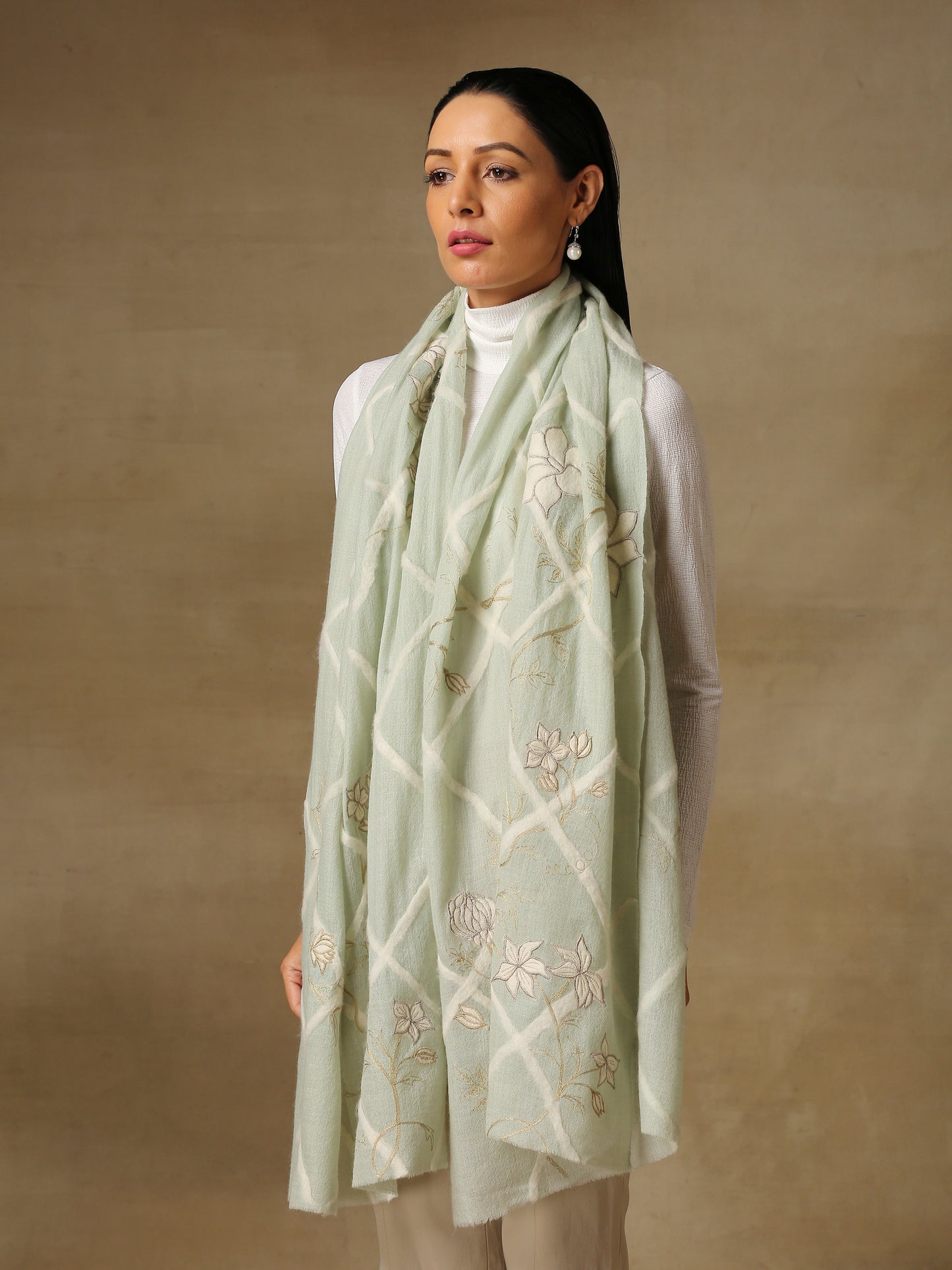 Model is wearing the Daisy pashmina stole in mint green from Shaza, featuring threadwork of interwoven lines and applique of daisy figures on handloomed pashmina.