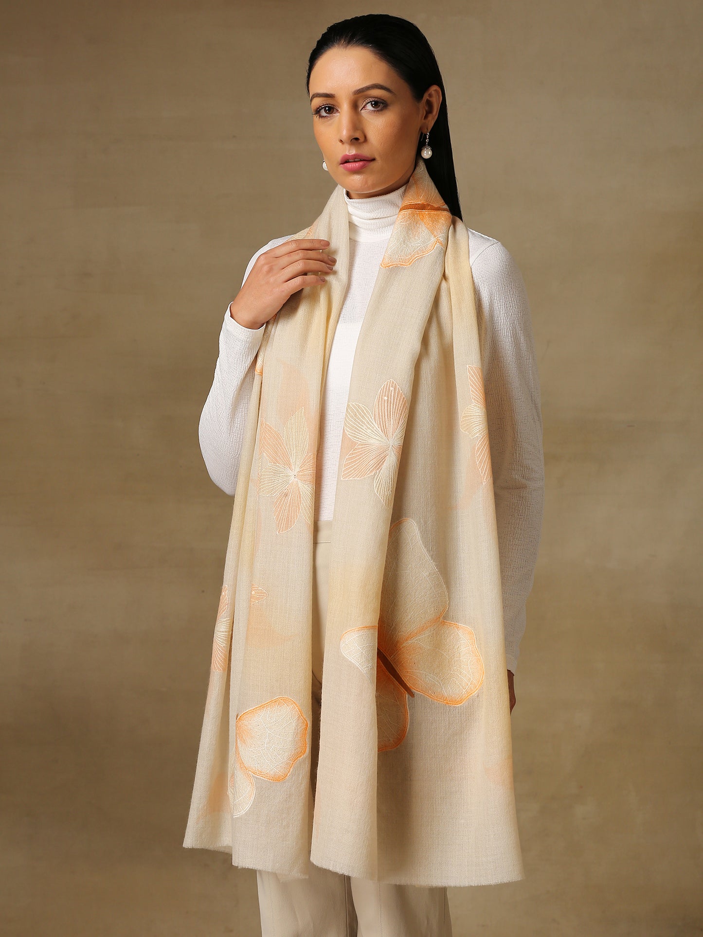 Model is wearing the butterfly pashmina stole from Shaza, featuring hand embroidered butterfly shapes decorated with swarovski on a cream pashmina stole.