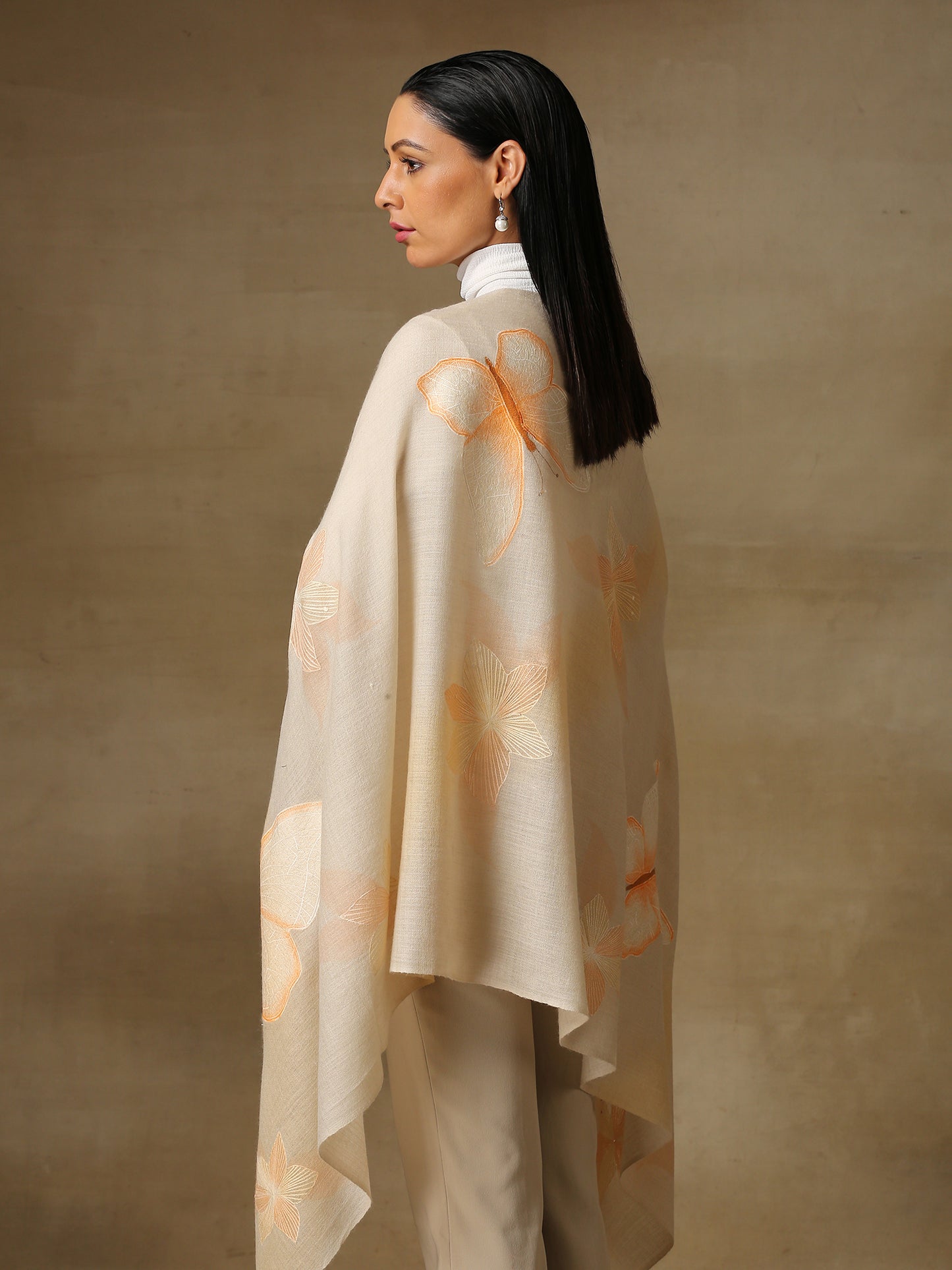 Model is wearing the butterfly pashmina stole from Shaza, featuring hand embroidered butterfly shapes decorated with swarovski on a cream pashmina stole.
