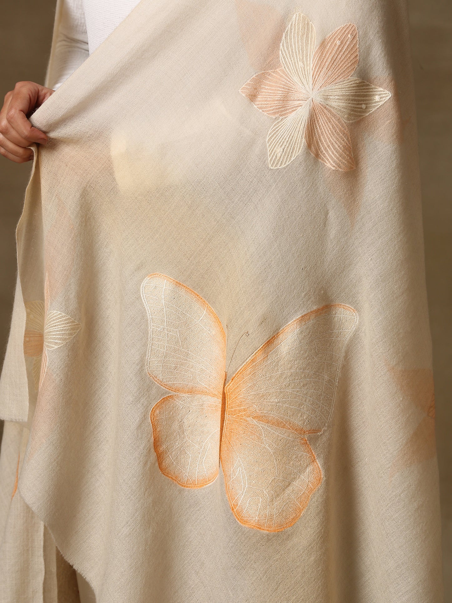 Model is wearing the butterfly pashmina stole from Shaza, featuring hand embroidered butterfly shapes decorated with swarovski on a cream pashmina stole.