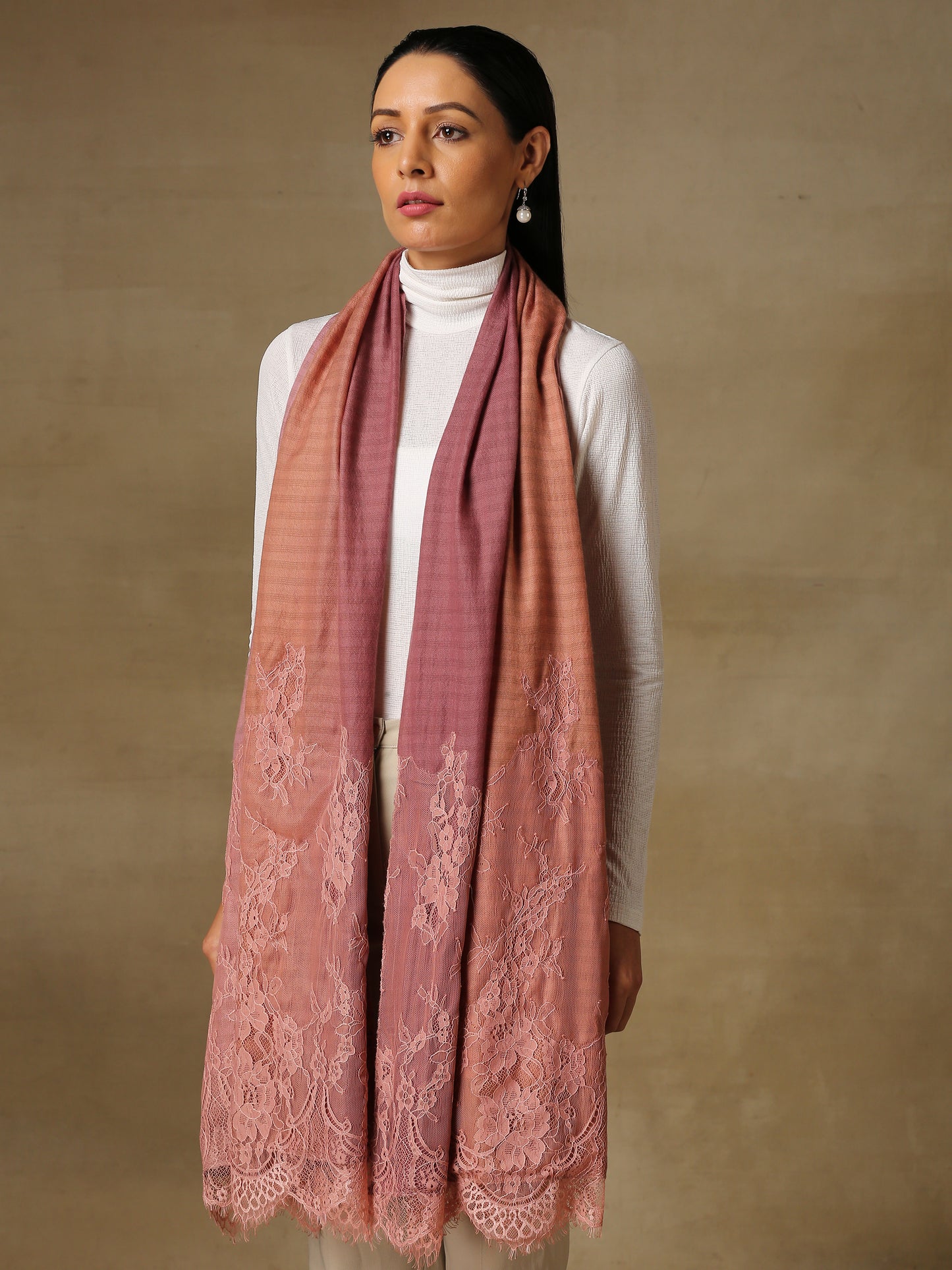 Model is wearing a pashmina stole in an ombre of mauve, lavishly embellished with floral motifs, made with threadwork, swarovski, pearls, and applique. This stole is from the Elements of spring collection.