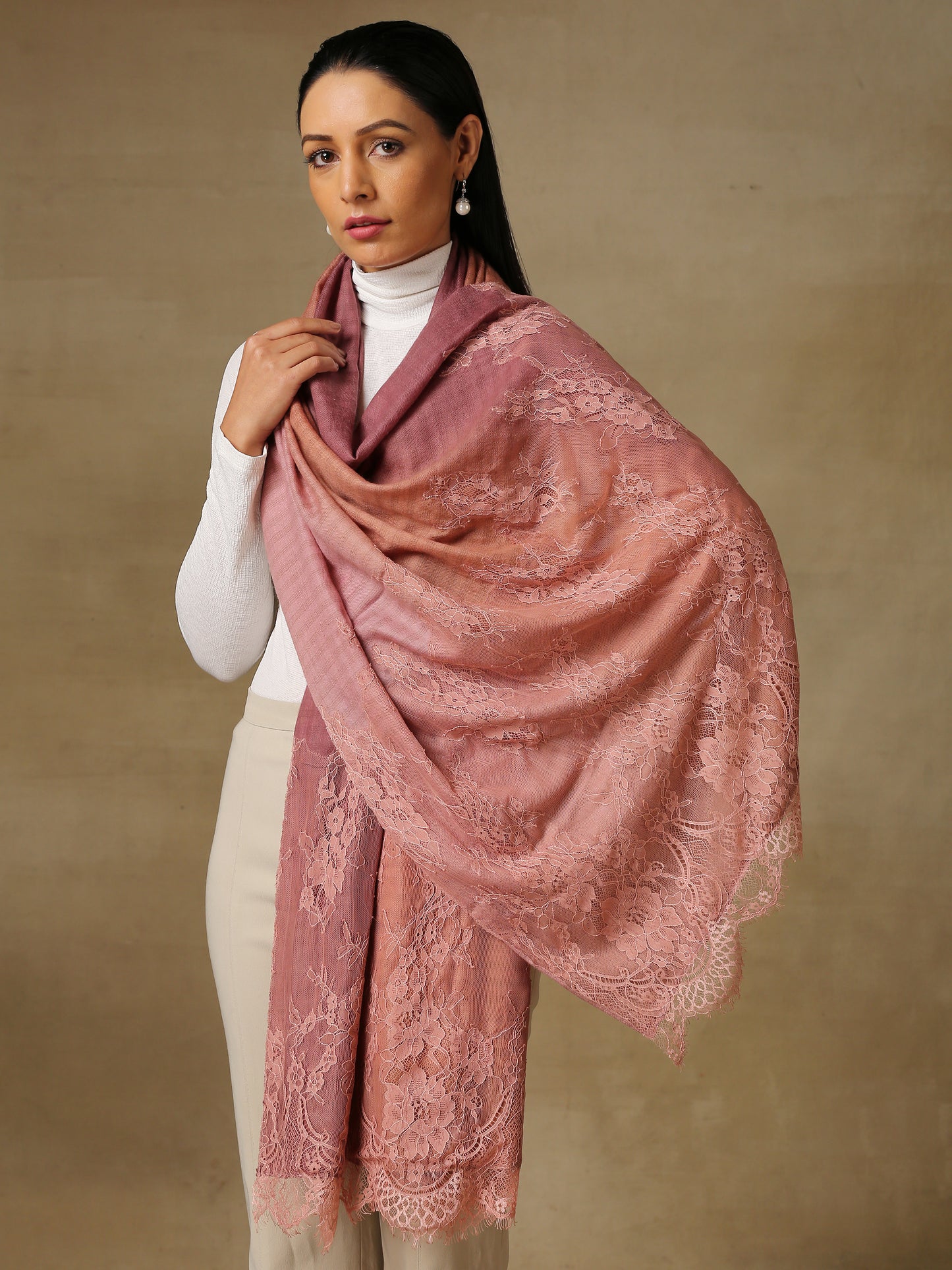 Model is wearing a pashmina stole in an ombre of mauve, lavishly embellished with floral motifs, made with threadwork, swarovski, pearls, and applique. This stole is from the Elements of spring collection.