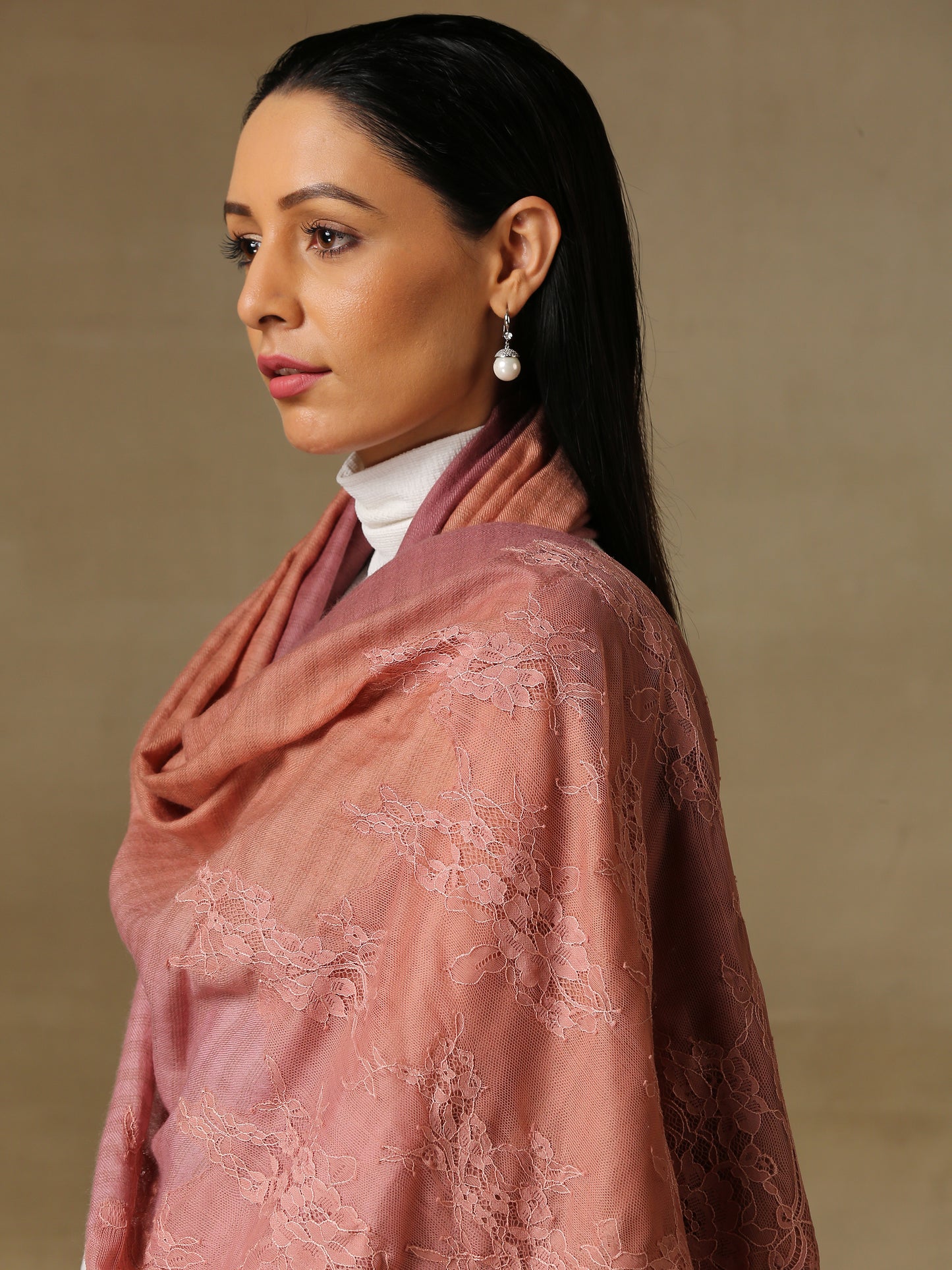 Model is wearing a pashmina stole in an ombre of mauve, lavishly embellished with floral motifs, made with threadwork, swarovski, pearls, and applique. This stole is from the Elements of spring collection.