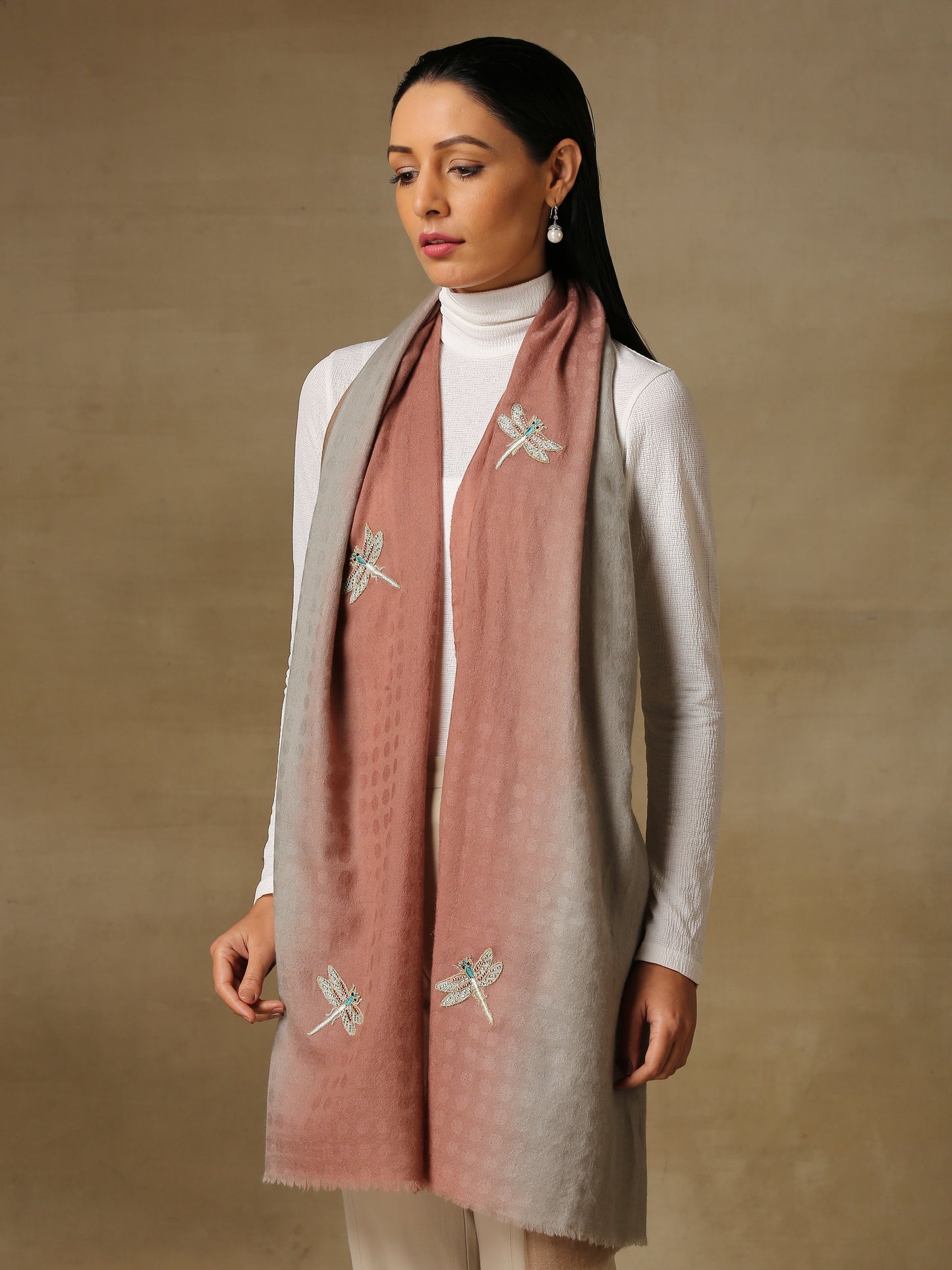 Model is wearing a Dragonfly stole in self weave handloomed pashmina featuring dragonflies hand embroidered using threadwork, pearls, cutdana and shellwork, on a handloomed mauve and brown pashmina.