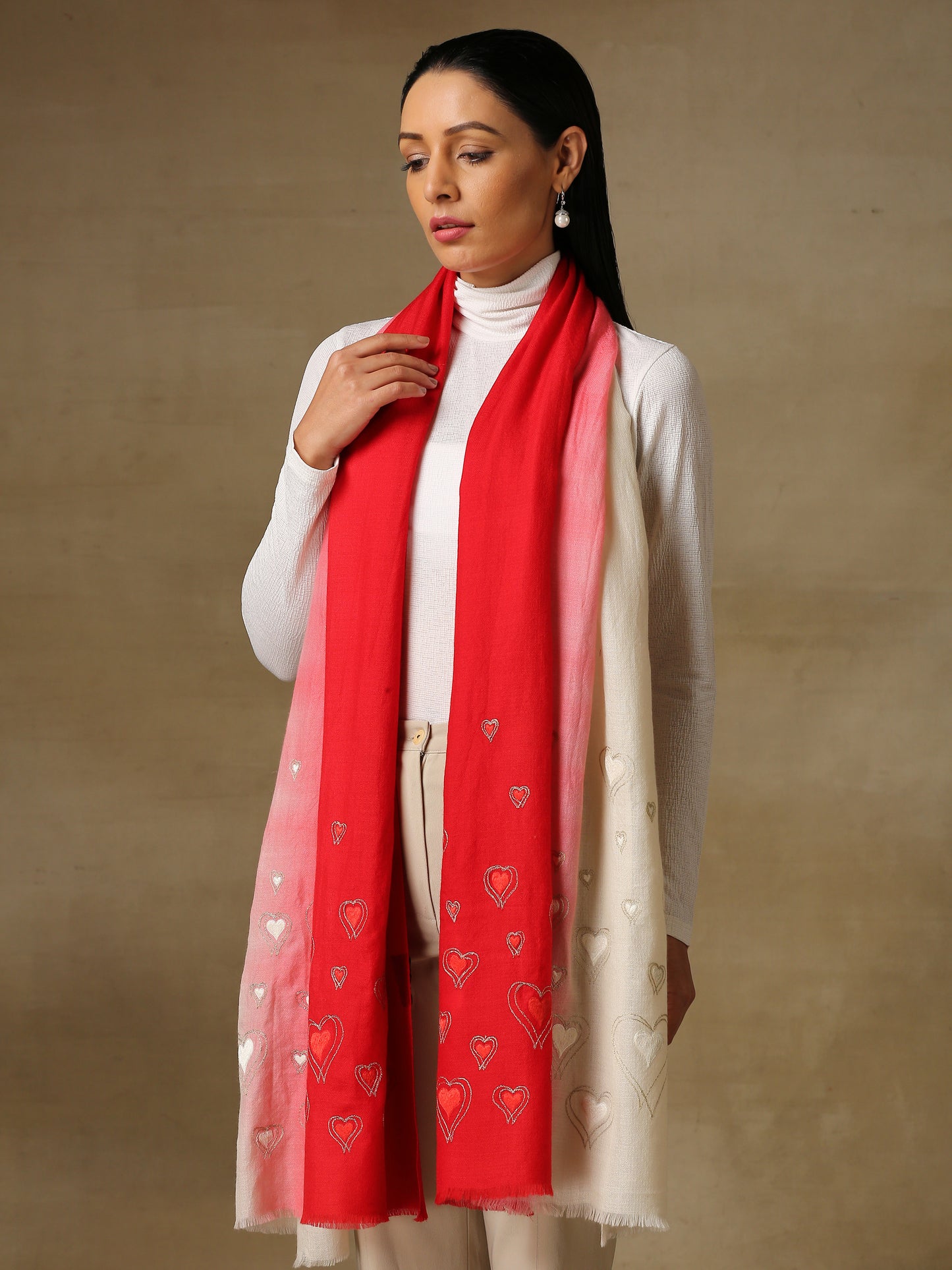 Model is wearing the Love tales pashmina stole in an ombre of white and red, from shaza, hand embroidered with heart shaped threadwork.