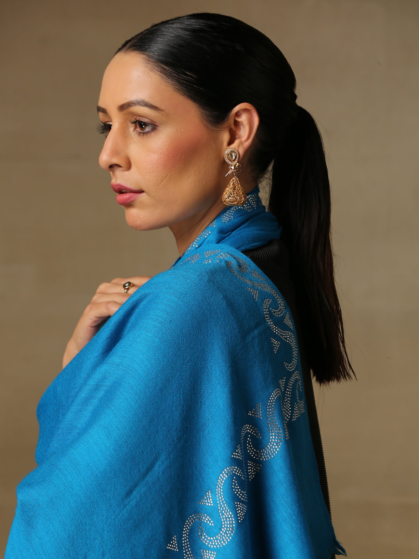 Model is wearing a firozi blue stole from the Era of Zaywar Border Swarovski Stole collection, hand embellished with fine silver swarovski in a waves design
