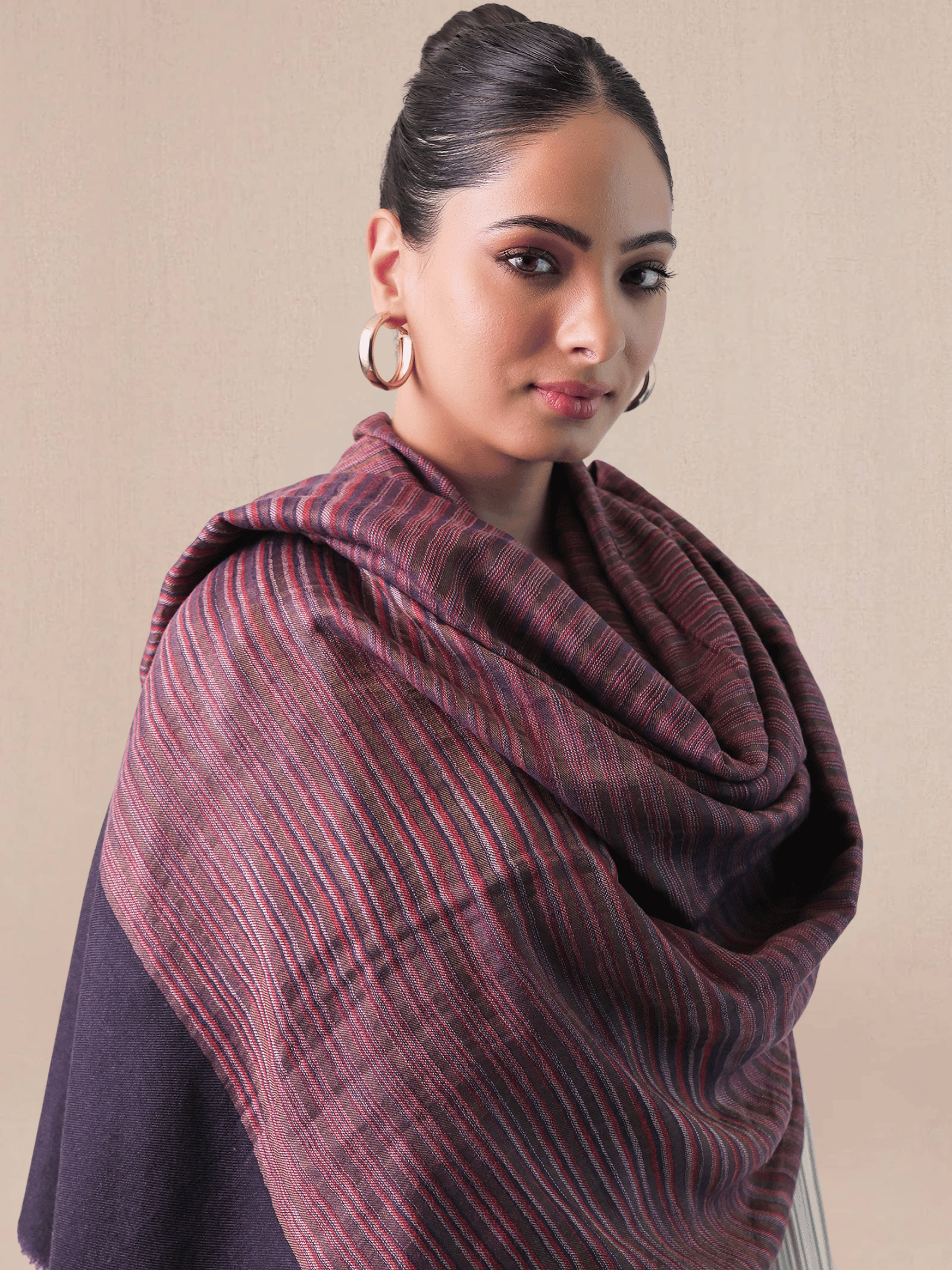Woman wearing a large purple scarf against a beige background