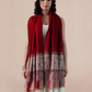A woman wearing a vibrant red pashmina shawl with intricate floral embroidery and mehrabs.
