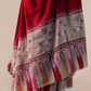 A woman wearing a vibrant red pashmina shawl with intricate floral embroidery and mehrabs.