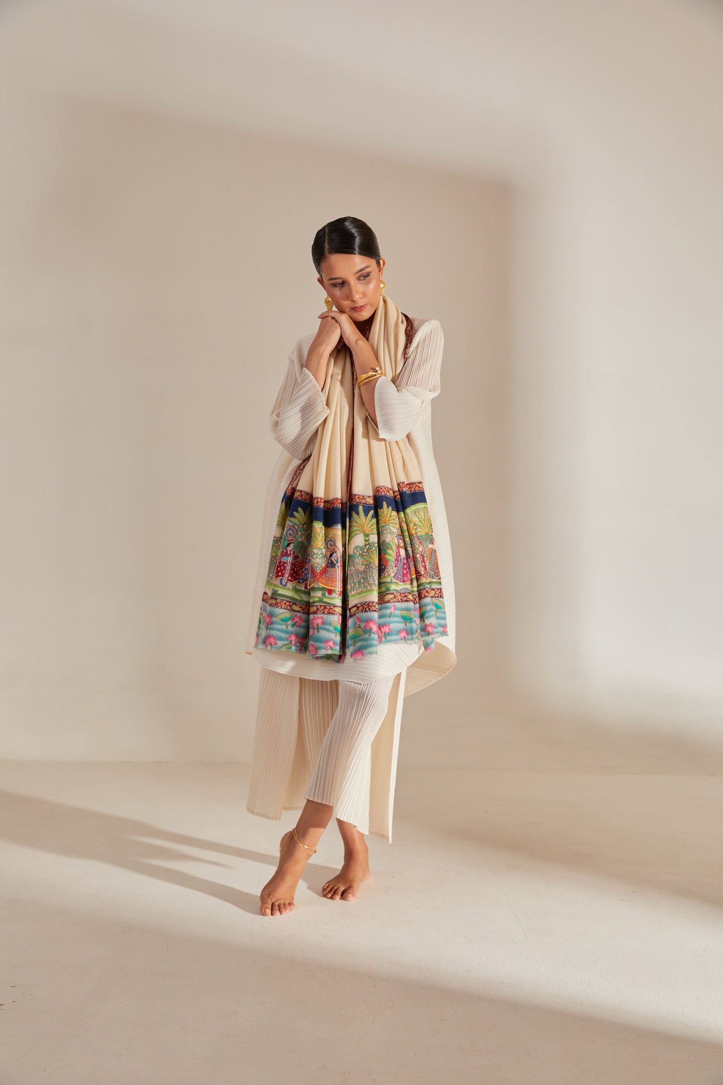 Model is wearing the Krishna Baraat Pashmina Shawl hand painted and hand embroidered on handloomed pashmina, depicting the secret wedding of Radha and Krishna, presided over by Lord Brahma. 