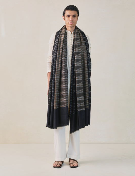 A man wearing a black, brown, and gray pashmina shawl with a geometric pattern.
