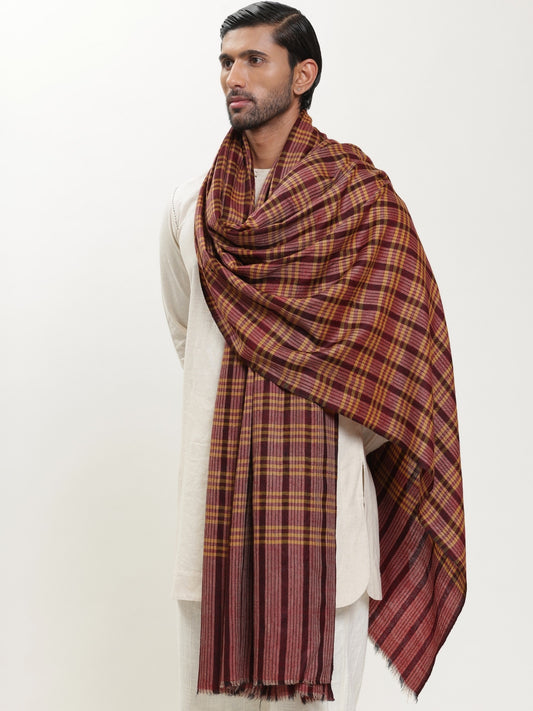 Man wearing a maroon and mustard check shawl.