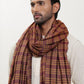 Man wearing a maroon and mustard check shawl.