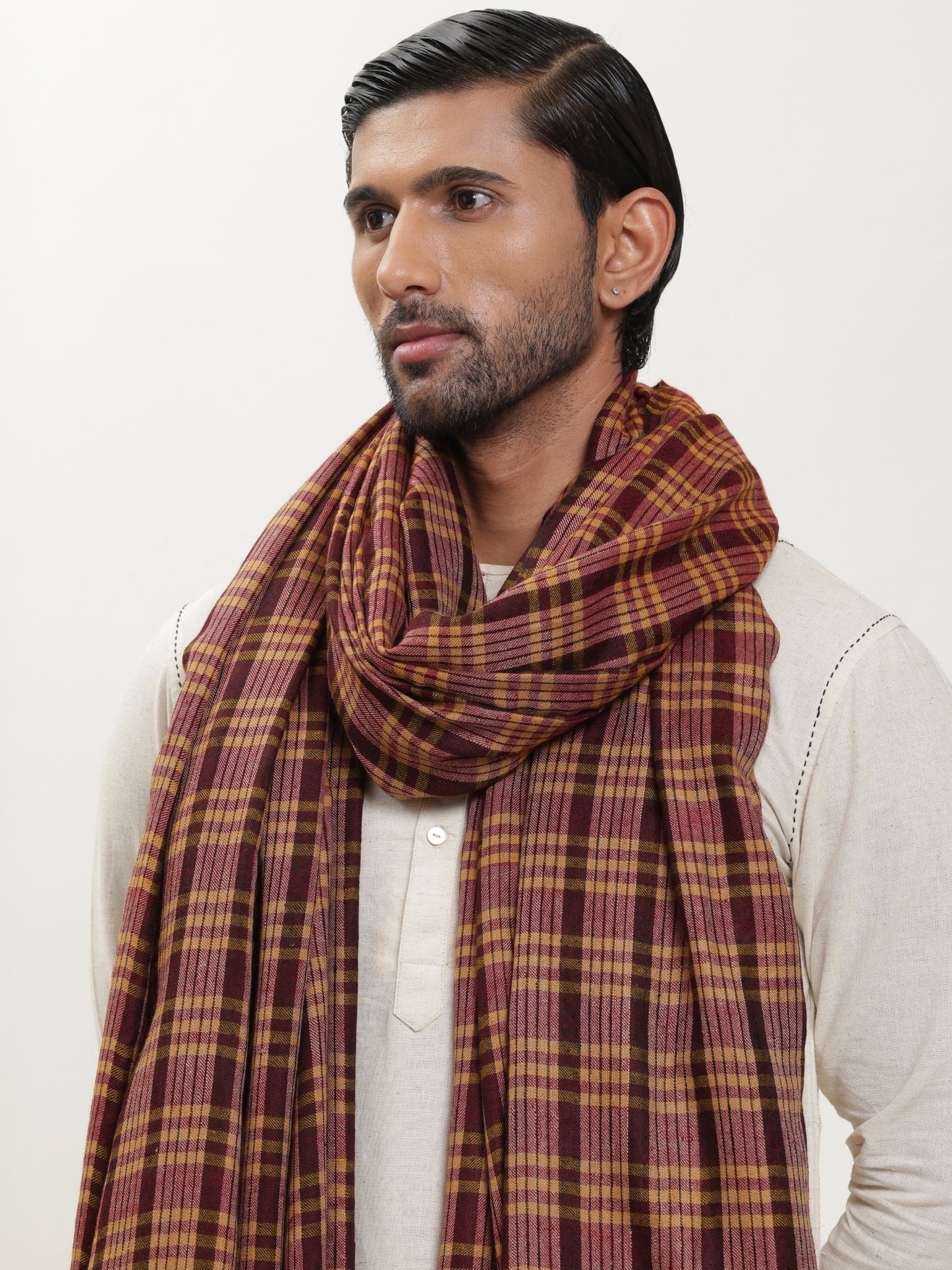 Man wearing a maroon and mustard check shawl.