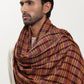 Man wearing a maroon and mustard check shawl.