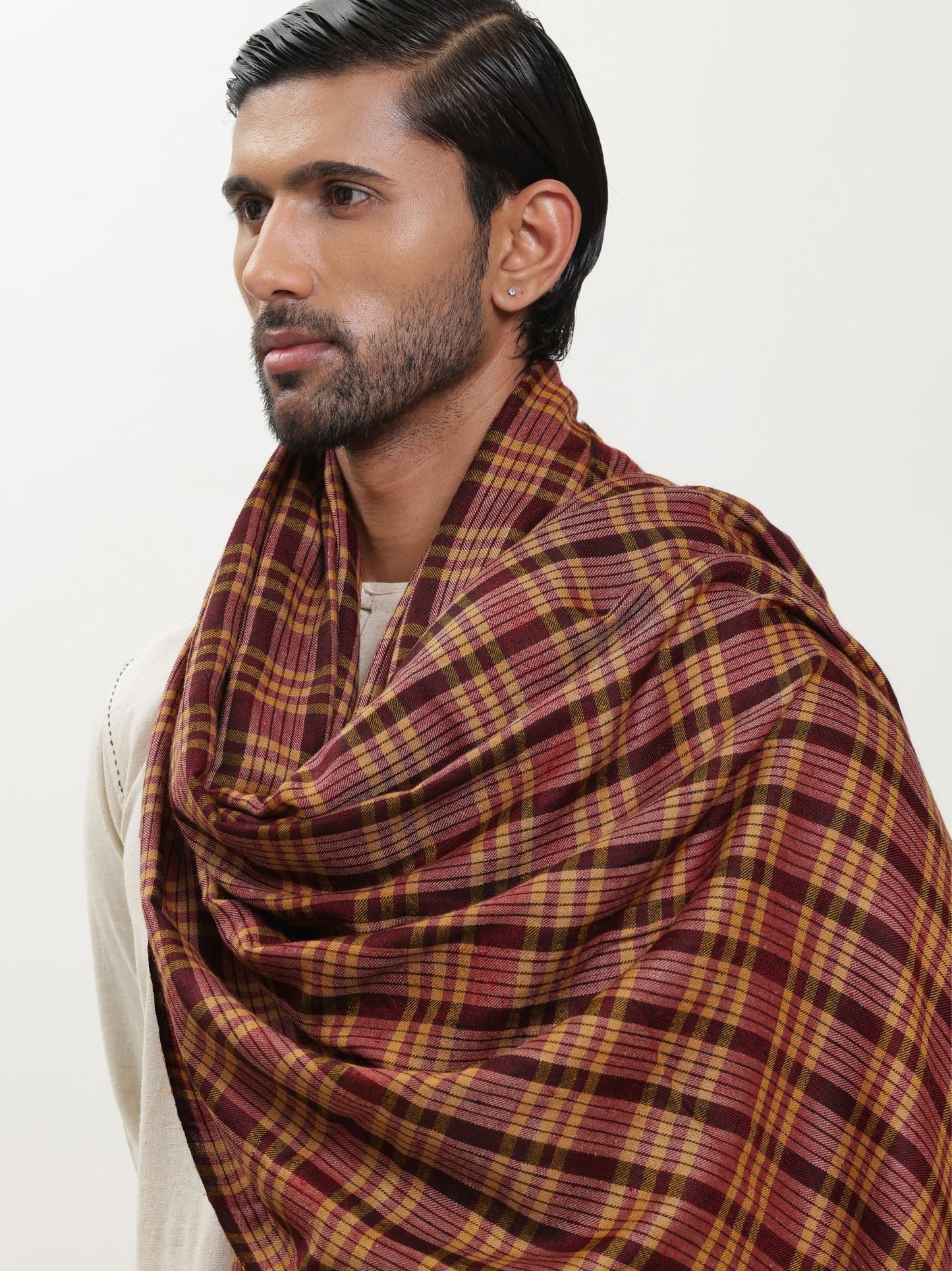 Man wearing a maroon and mustard check shawl.