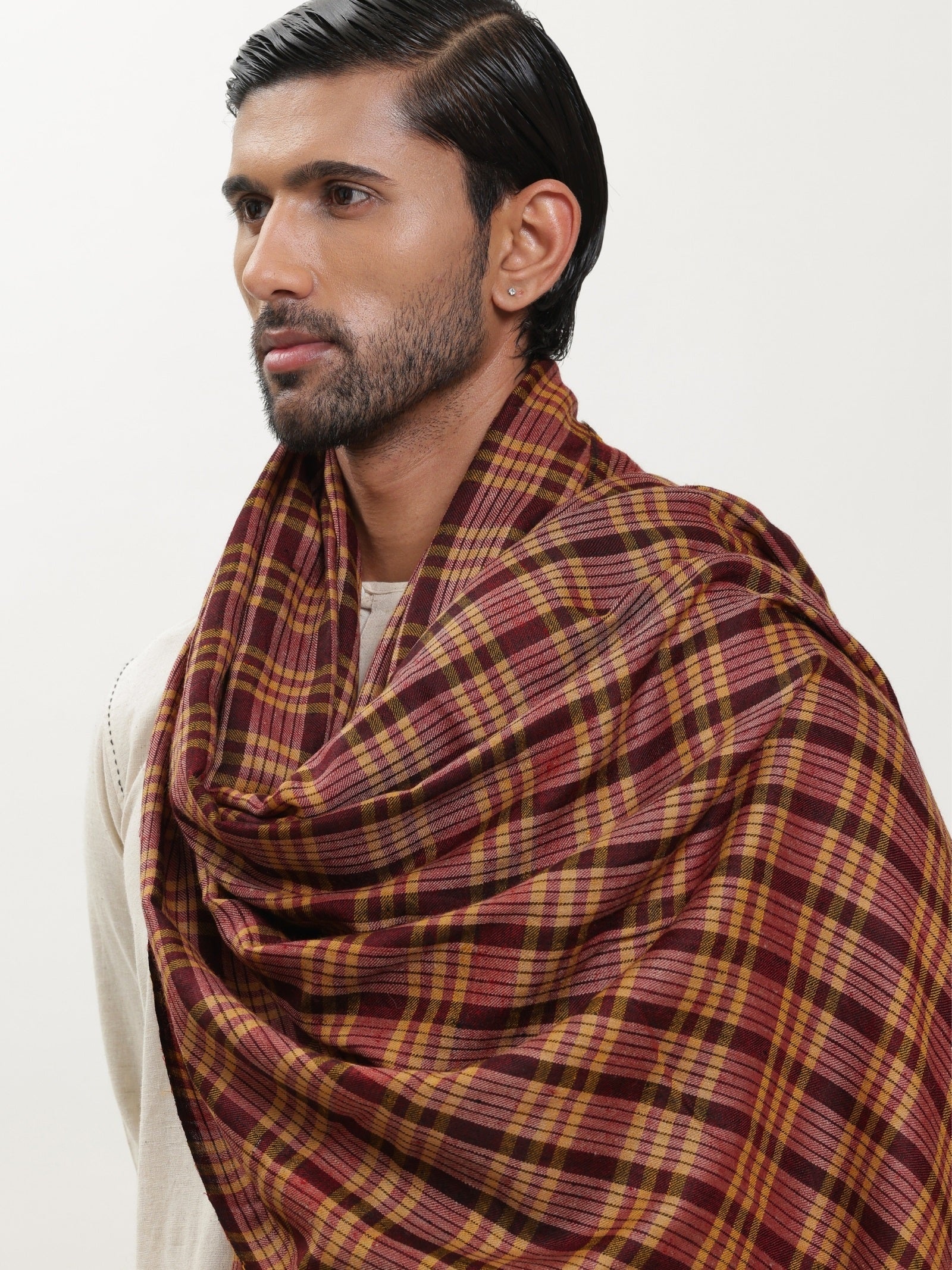 Man wearing a maroon and mustard check shawl.