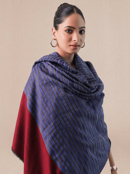 A woman wearing a pashmina shawl with a striped pattern in red and blue hues.