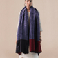 A woman wearing a pashmina shawl with a striped pattern in red and blue hues.