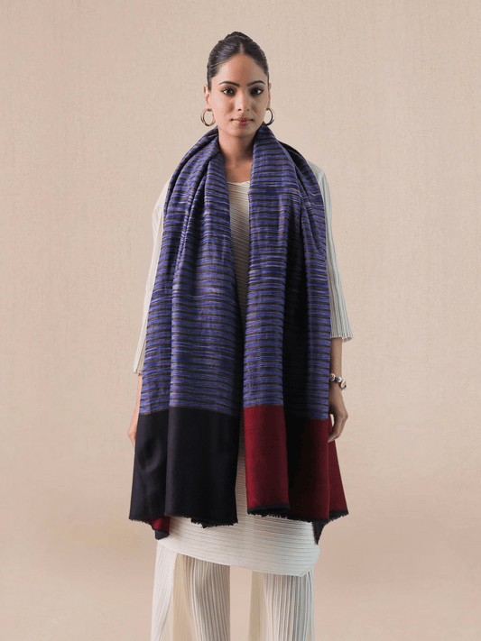 A woman wearing a pashmina shawl with a striped pattern in red and blue hues.