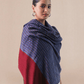 A woman wearing a pashmina shawl with a striped pattern in red and blue hues.