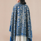 A woman wearing a royal blue pashmina shawl with intricate gold and silver zari embroidery in floral and paisley motifs, and a floral border.