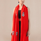 A woman wearing a bright red pashmina stole with embroidered motifs.