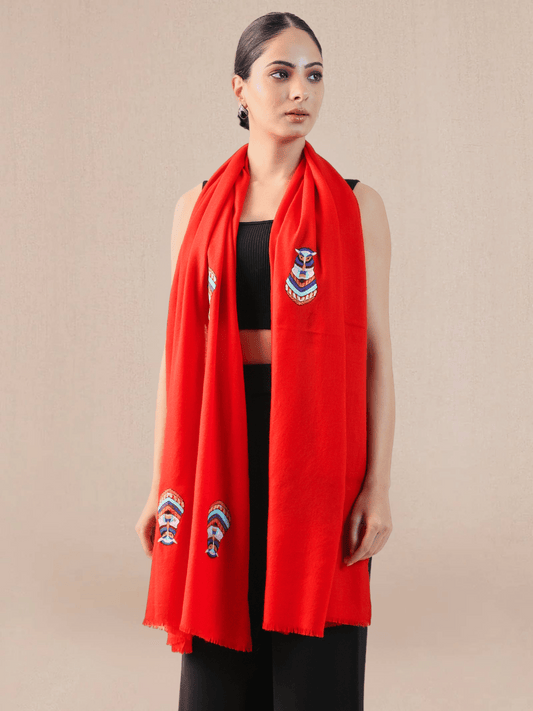 A woman wearing a bright red pashmina stole with embroidered motifs.