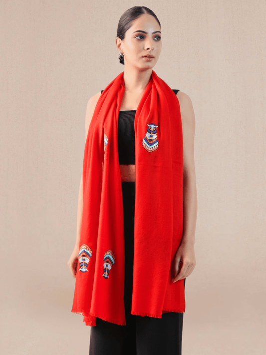 A woman wearing a bright red pashmina stole with embroidered motifs.