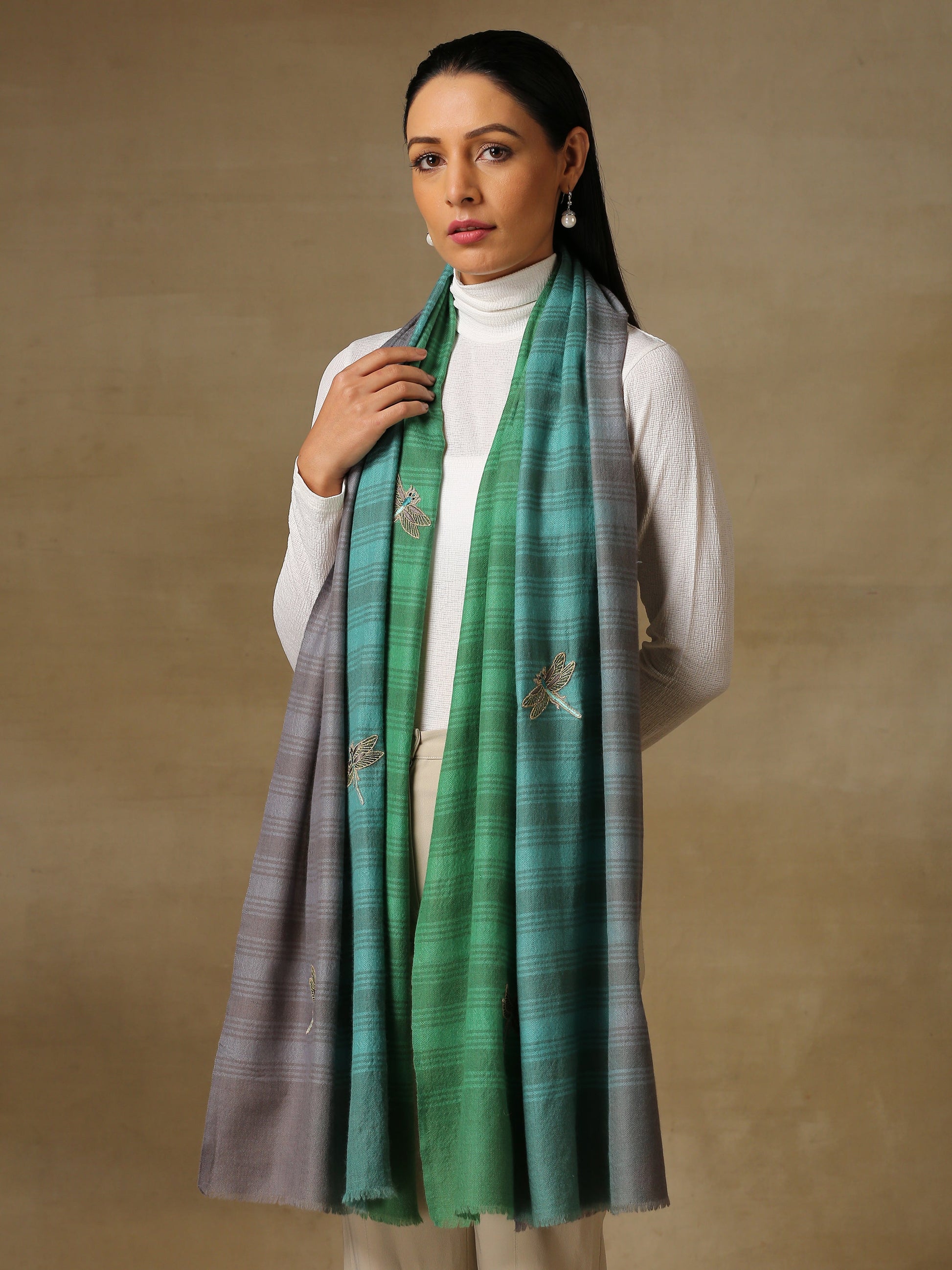 Model is wearing a Dragonfly stole in self weave handloomed pashmina featuring dragonflies hand embroidered using threadwork, pearls, cutdana and shellwork, on a handloomed sea green ombre pashmina. 