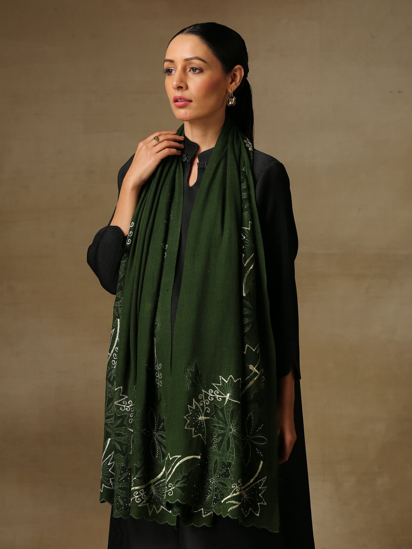 Model is wearing a Vineyard Zaywar stole featuring cutwork vine pattern bordered with zari details and hand embellished with fine swarovski, in a green colour. 