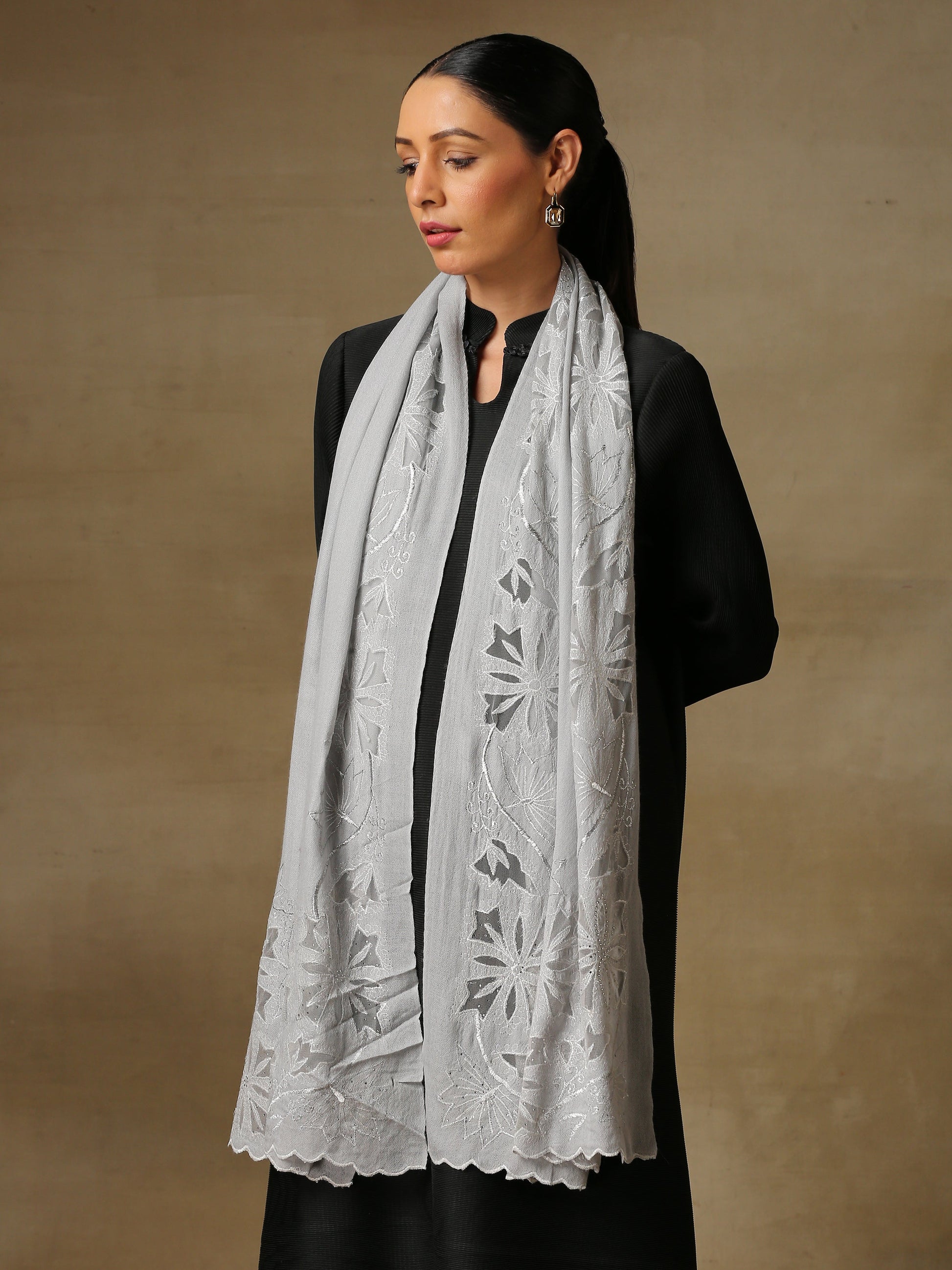 Model is wearing a Vineyard Zaywar stole featuring cutwork vine pattern bordered with zari details and hand embellished with fine swarovski, in a ice blue colour. 