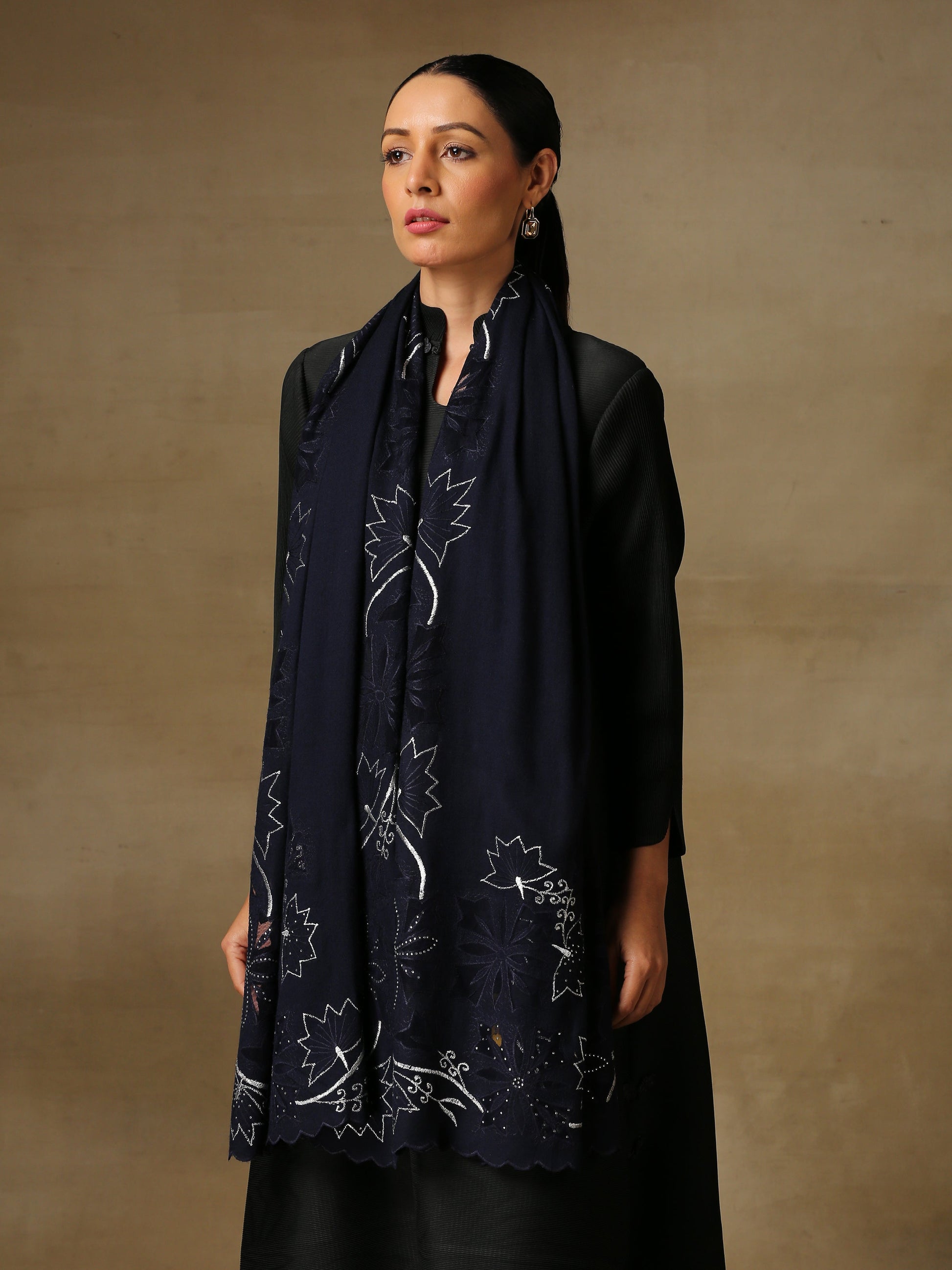 Model is wearing a Vineyard Zaywar stole featuring cutwork vine pattern bordered with zari details and hand embellished with fine swarovski, in a midnight blue colour. 