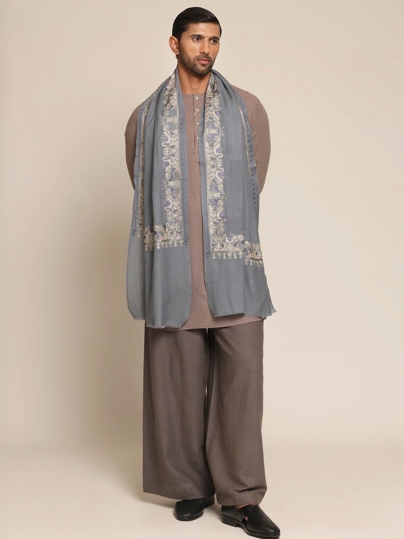 Man wearing a traditional outfit with a baby blue embroidered stole.
