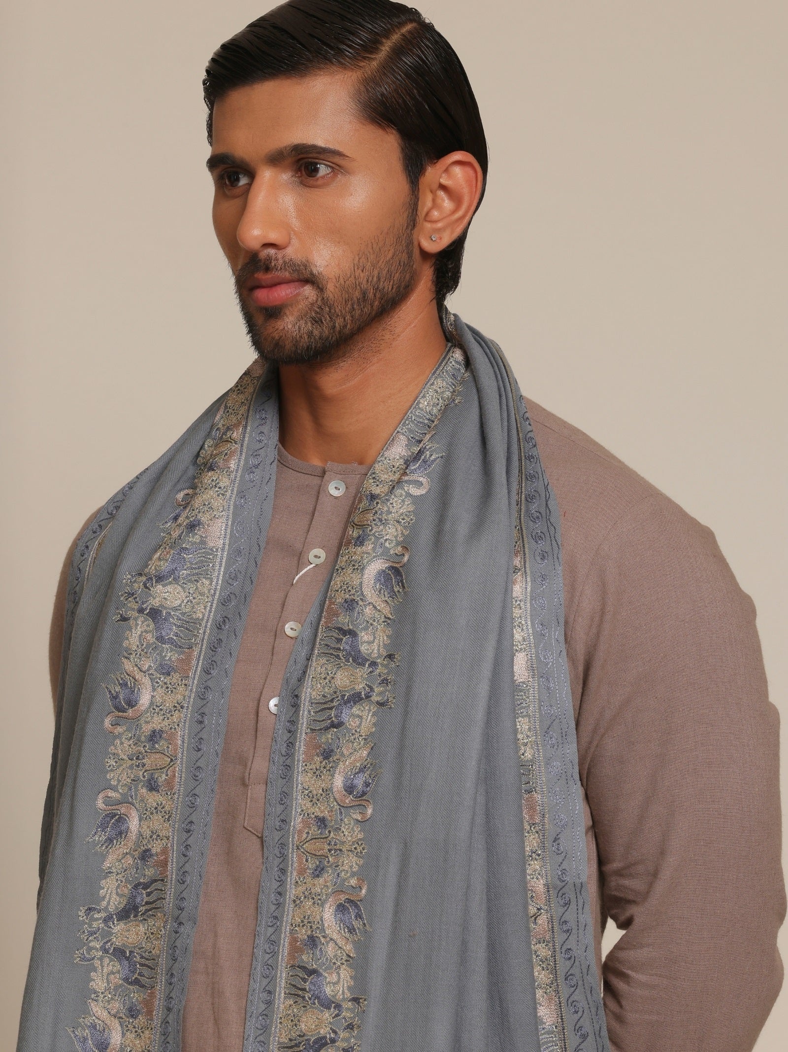 Man wearing a traditional outfit with a baby blue embroidered stole.