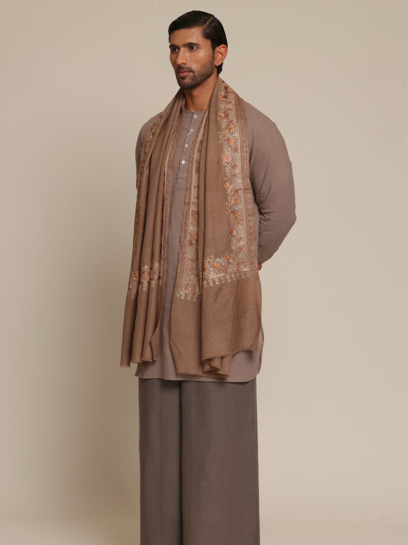 Man wearing a brown traditional outfit with a woolen stole