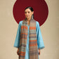 Model is wear a pashmina check stole featuring multi colored stripes on a toosh coloured base.