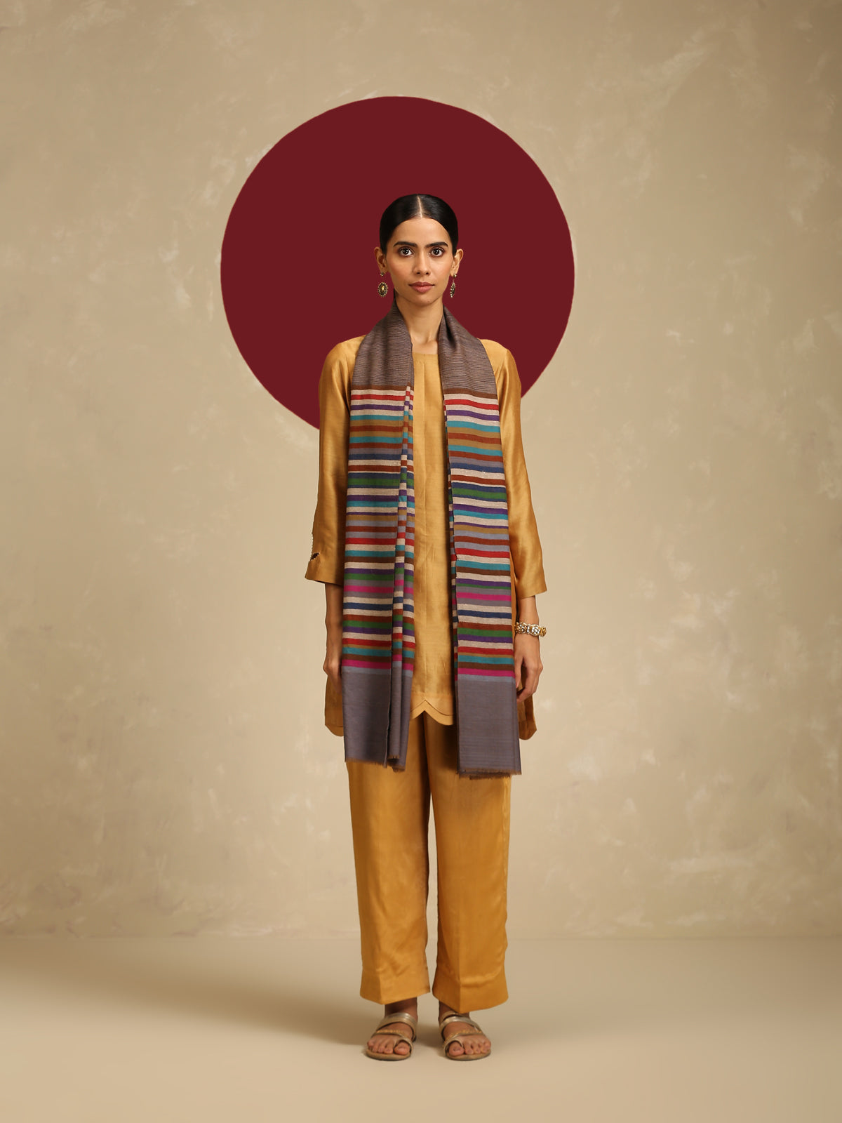 Model is wearing Qazah Stole with multicoloured stripes on a gray base  