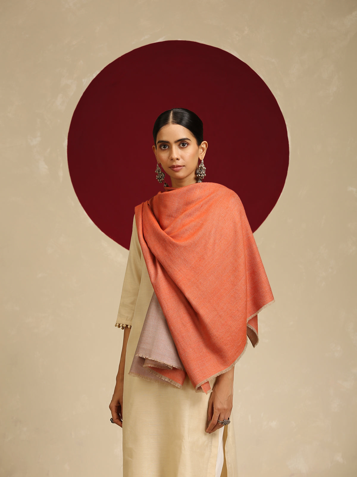Model is wearing pashmina reversible shawl in orange with natural at the back.