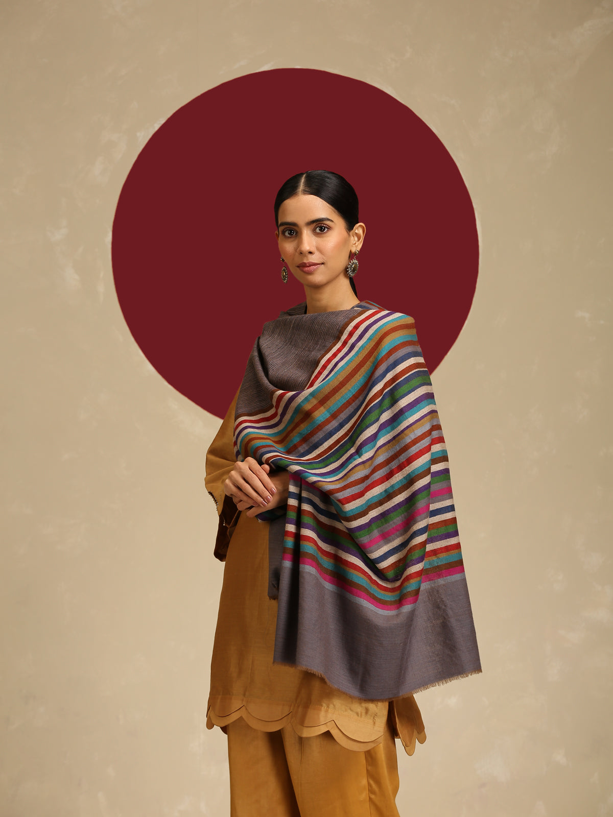 Model is wearing Qazah Stole with multicoloured stripes on a gray base  
