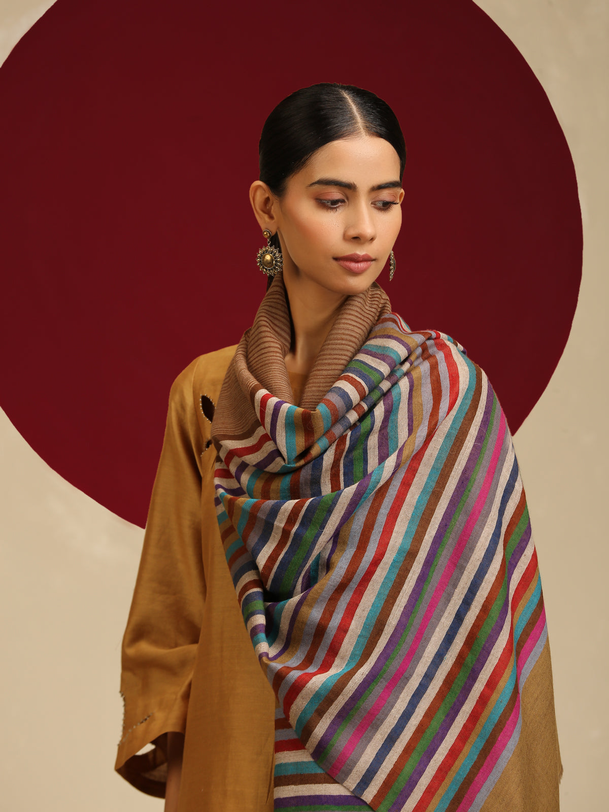 Model is wearing a Qazah stole featuring multicoloured stripes on a gold base.