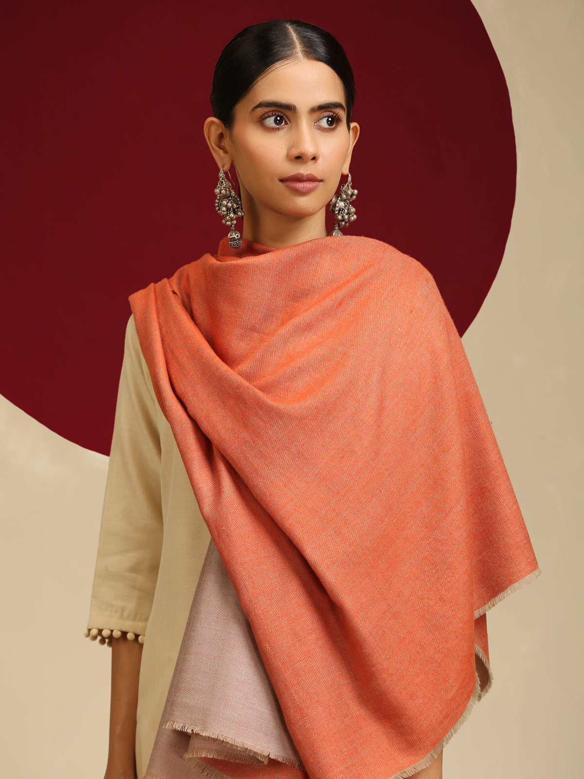 Model is wearing pashmina reversible shawl in orange with natural at the back.
