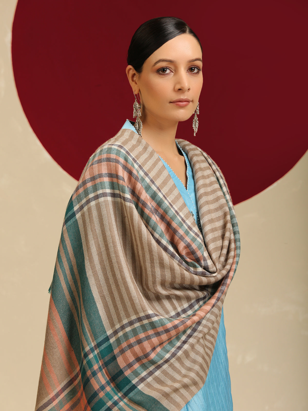 Model is wearing a pashmina check stole in multicoloured hues of orange, blue and green stripes/crosslines on a natural base.