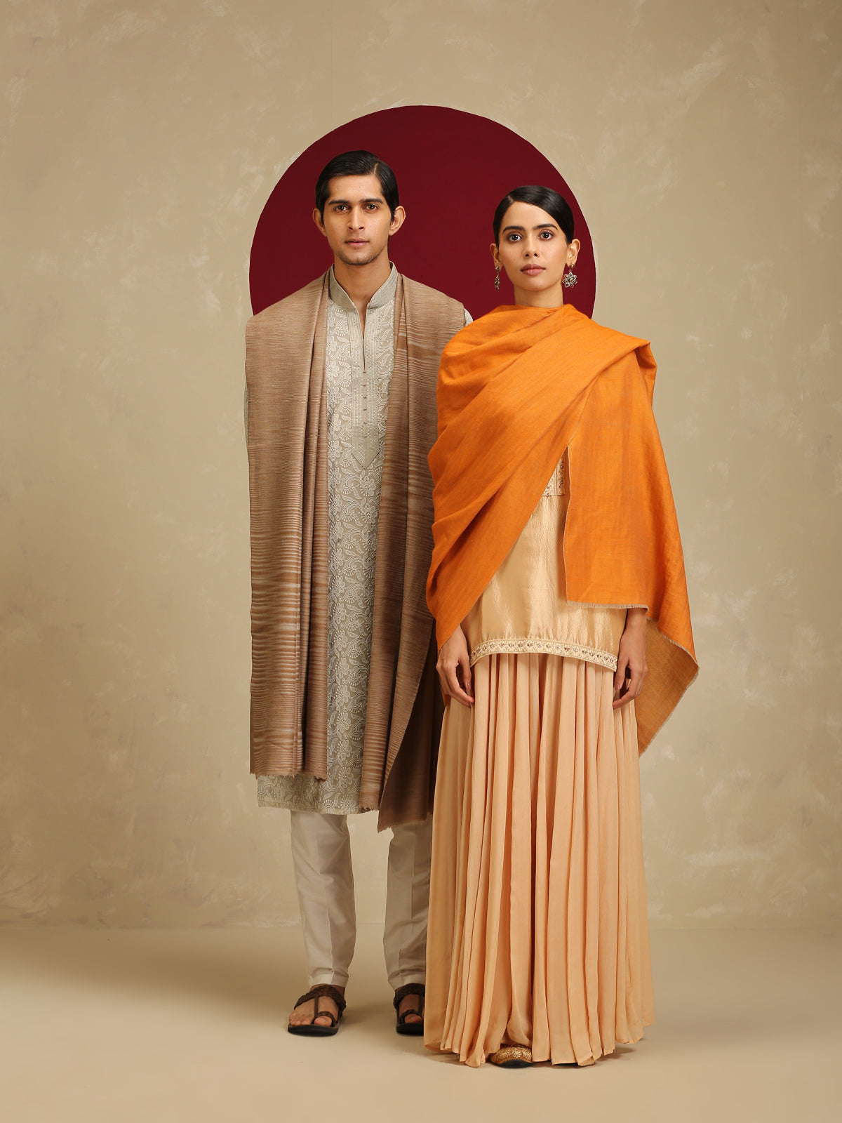 Model is wearing pashmina reversible shawl in orange with gold at the back.